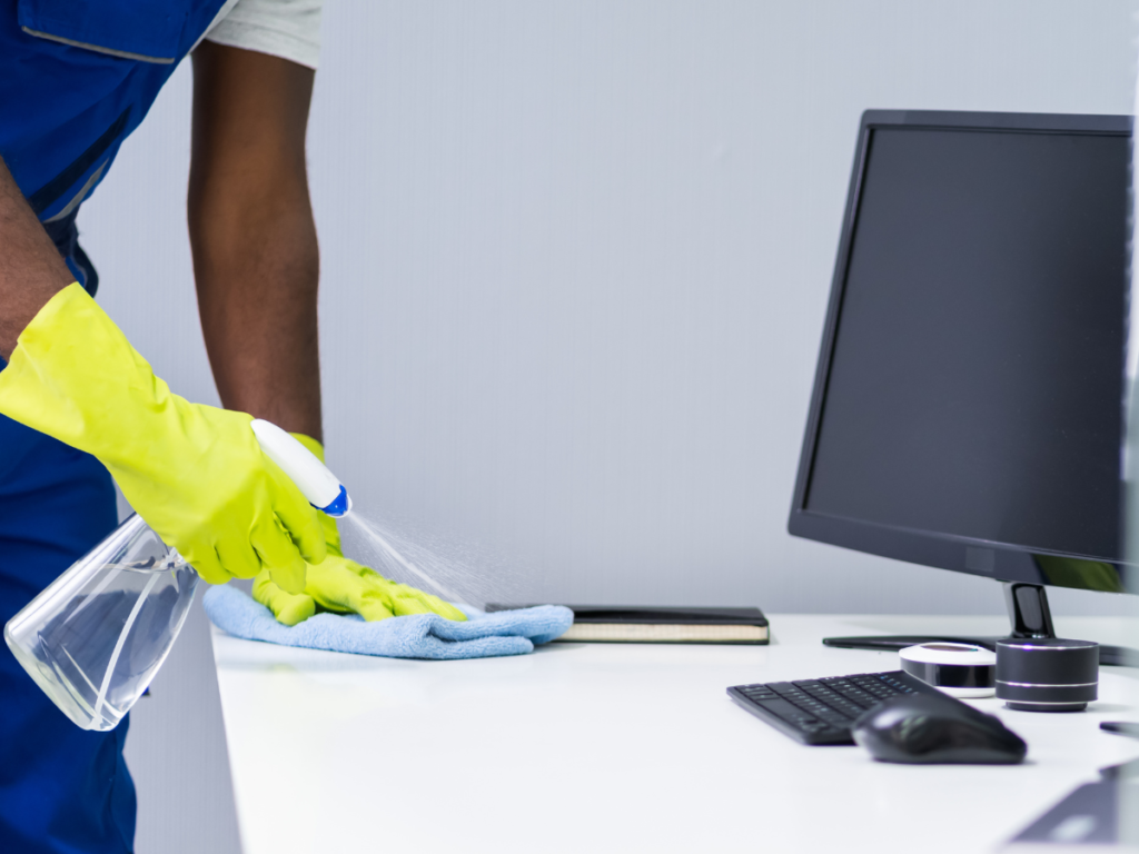 someone cleaning an office space with spray and a microfiber cloth 