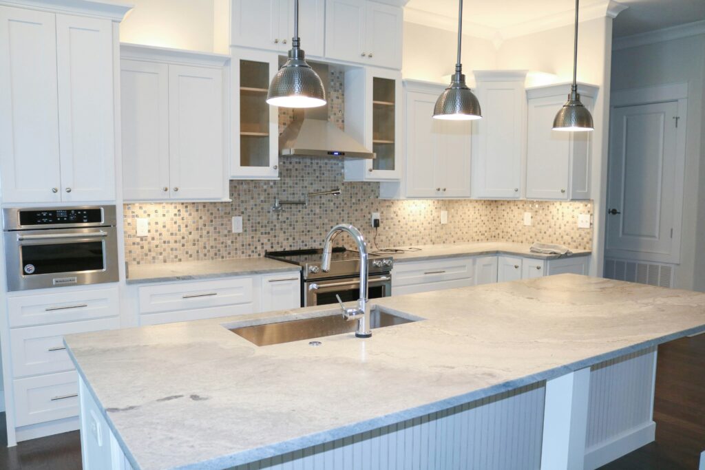 bright clean large kitchen with white stone countertops and white cabinets