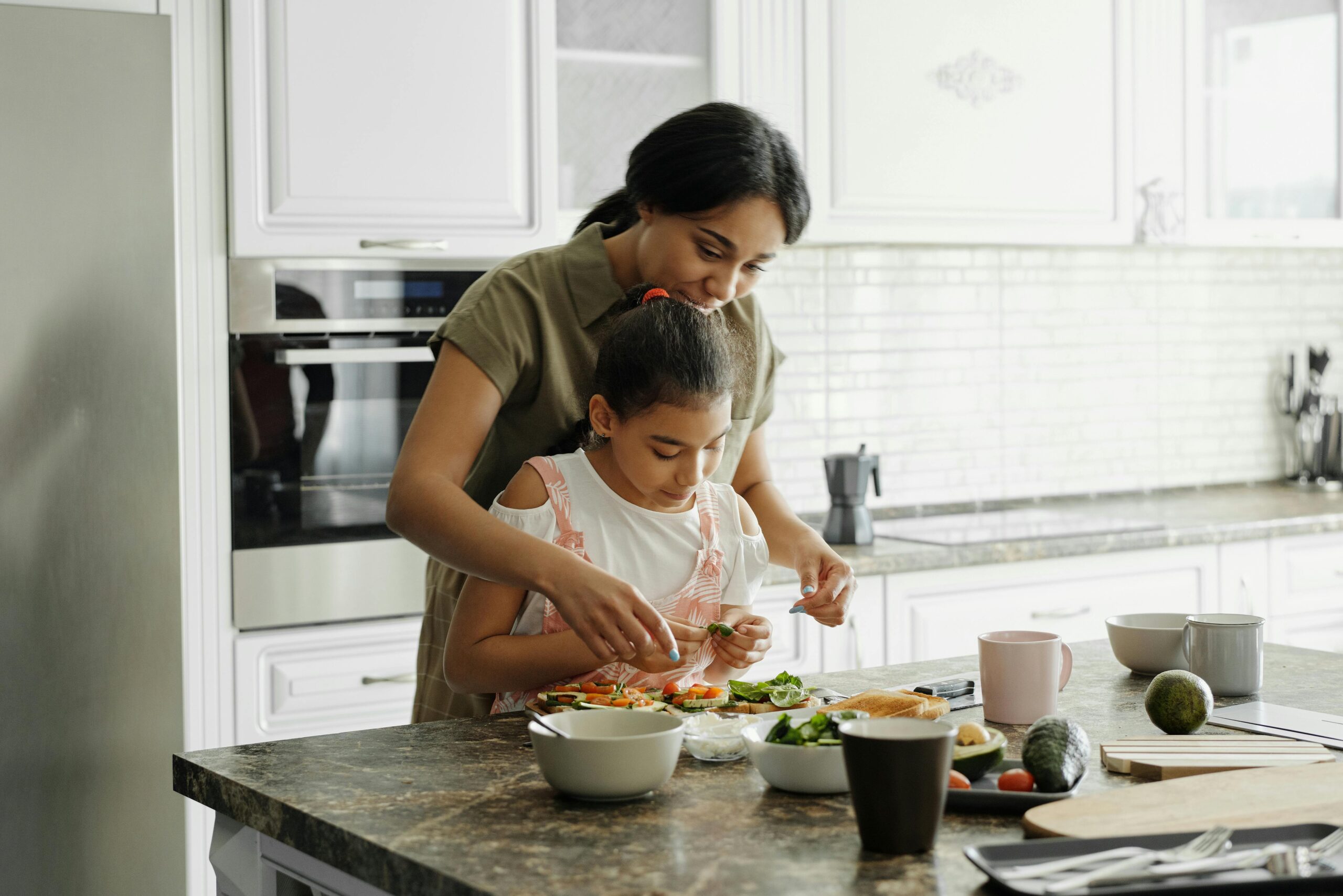 a mother and daughter making avocado toast in a bright, clean, modern kitchen