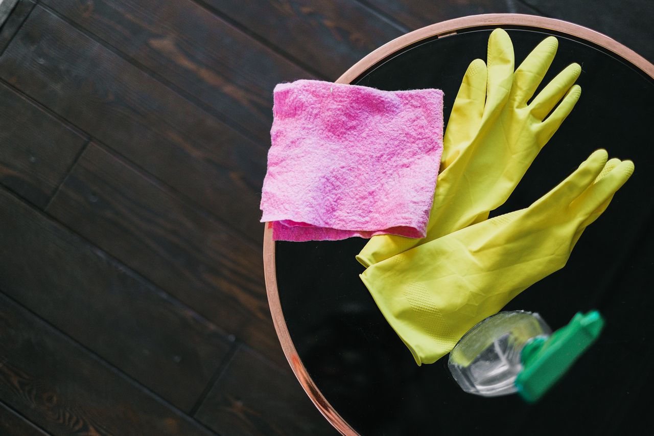 yellow gloves, pink cloth, and spray bottle sitting on table